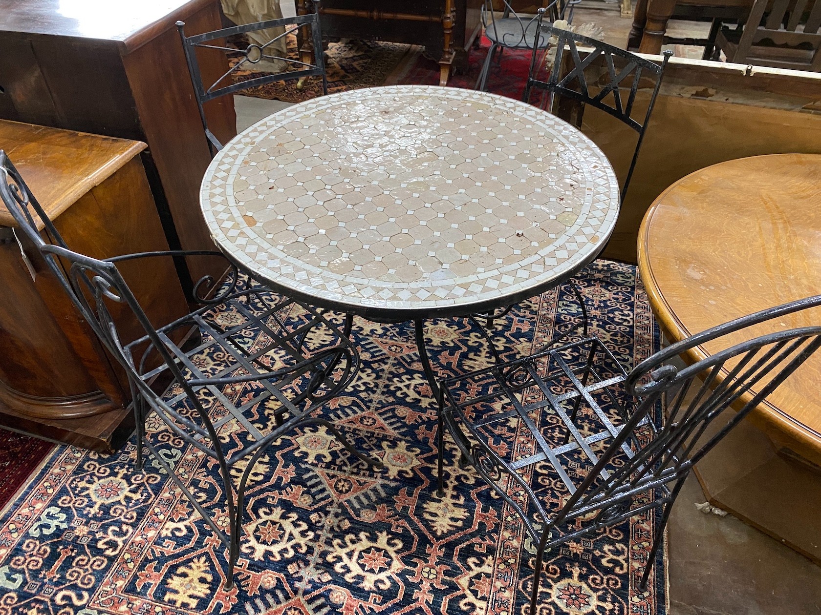 A circular mosaic top wrought iron garden table, diameter 100cm, height 74cm together with four wrought iron garden chairs, two with arms